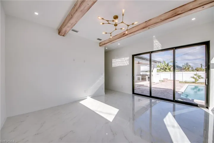Empty room featuring a chandelier and beam ceiling