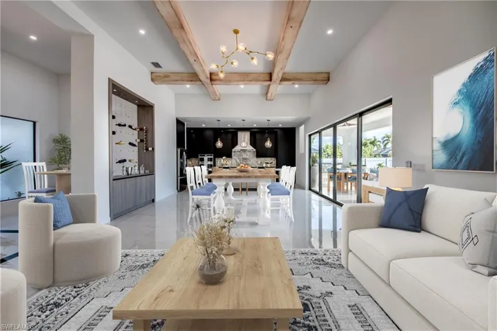 Virtually staged Living room featuring beamed ceiling, a high ceiling, and a chandelier