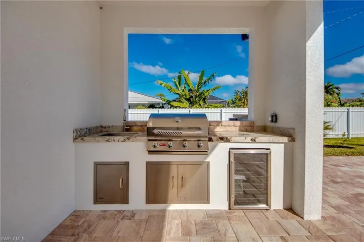 View of patio featuring area for grilling, a grill, sink, and beverage cooler