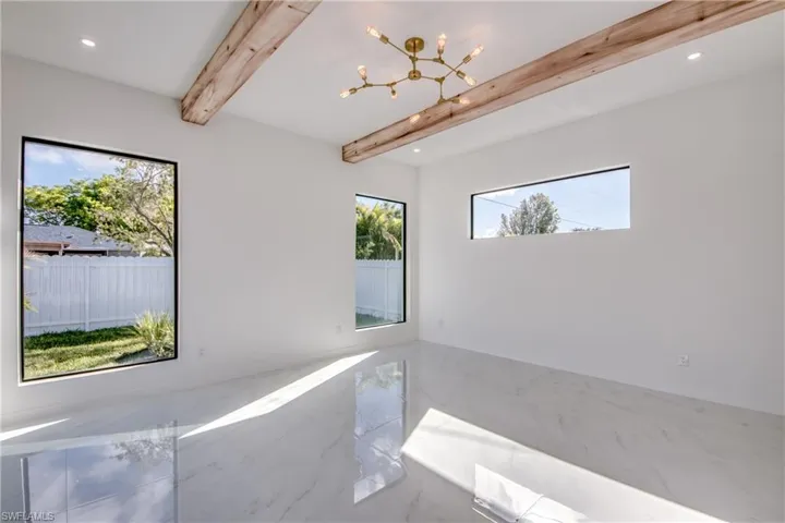 Spare room with beam ceiling and an inviting chandelier