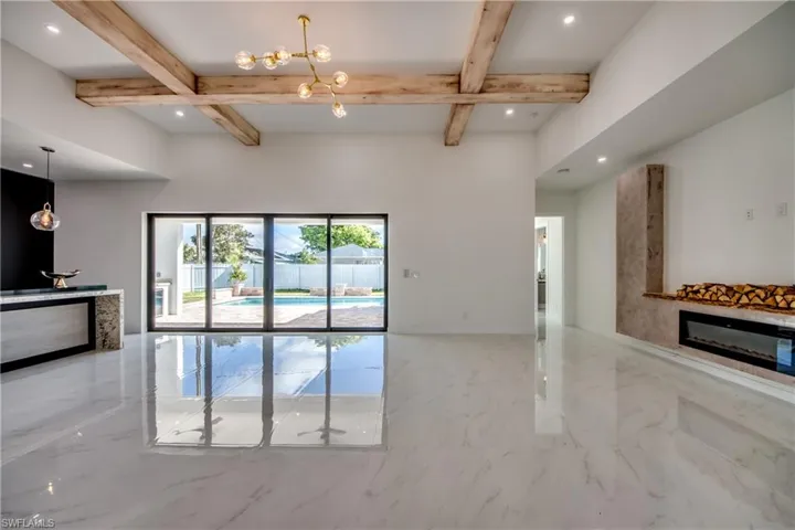 Unfurnished living room featuring beamed ceiling, a chandelier, and coffered ceiling