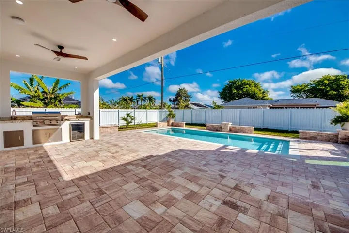 View of pool featuring an outdoor kitchen, area for grilling, ceiling fan, sink, and a patio area