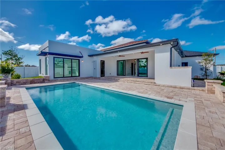Back of house featuring a fenced in pool, ceiling fan, and a patio