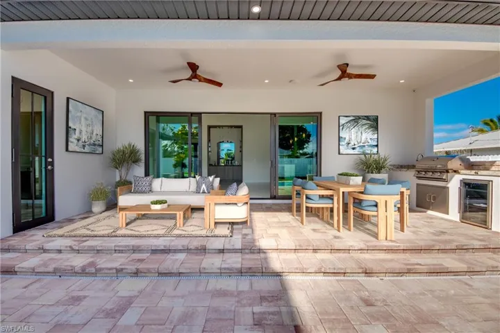 View of patio featuring ceiling fan, outdoor lounge area, area for grilling, beverage cooler, and exterior kitchen