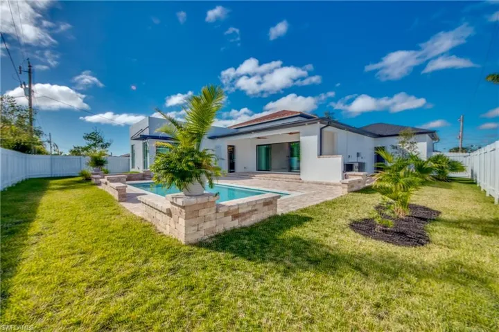 Rear view of house with a yard, a fenced in pool, a patio, and ceiling fan