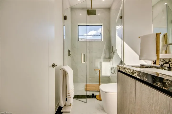 Bathroom with vanity, toilet, and a shower with shower door
