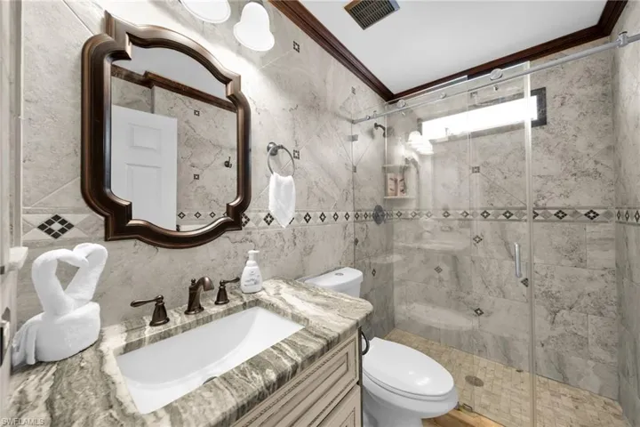 Full bathroom with tile walls, a stall shower, vanity, ornamental molding, and tasteful backsplash
