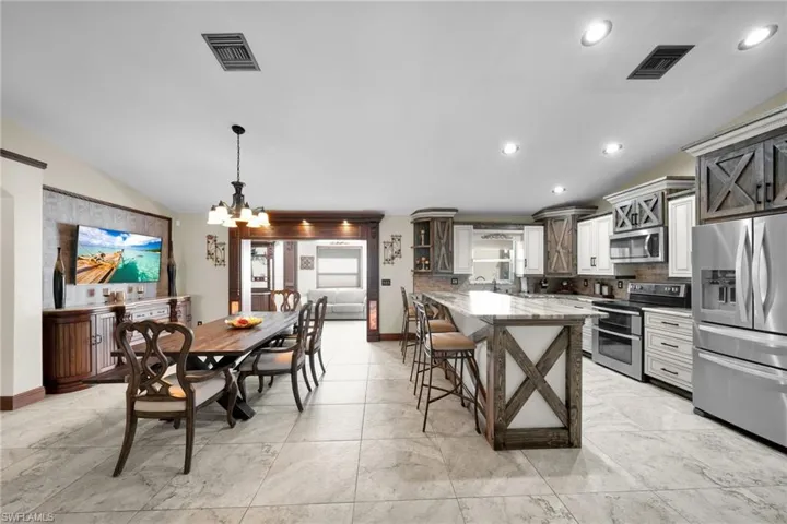 Kitchen with vaulted ceiling, appliances with stainless steel finishes, a kitchen breakfast bar, decorative backsplash, and decorative light fixtures