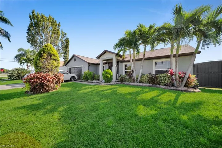 Ranch-style house with stucco siding, a front yard, and a garage