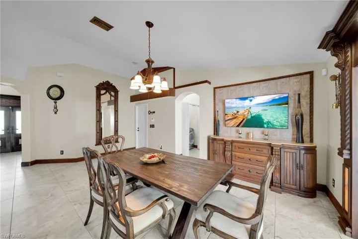 Dining area featuring arched walkways, vaulted ceiling, and a chandelier