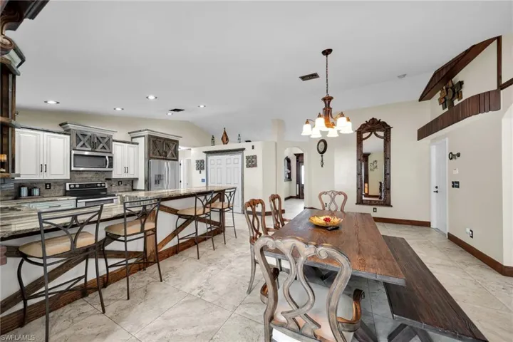 Dining room with arched walkways, vaulted ceiling, a chandelier, recessed lighting, and light tile patterned floors