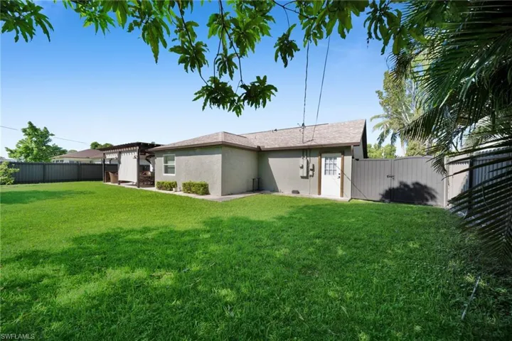 Back of property with a fenced backyard, a gate, and stucco siding