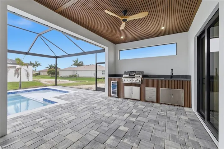 View of patio / terrace with an outdoor kitchen, a ceiling fan, an outdoor pool, a sunroom, and glass enclosure