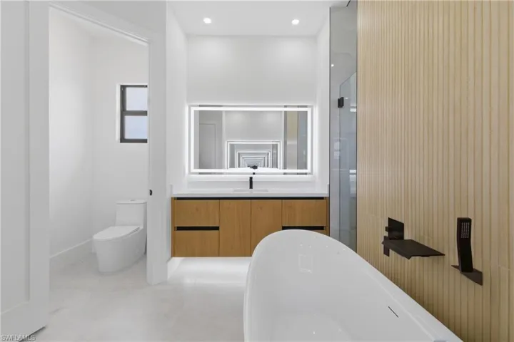 Bathroom featuring vanity, a stall shower, a soaking tub, and recessed lighting