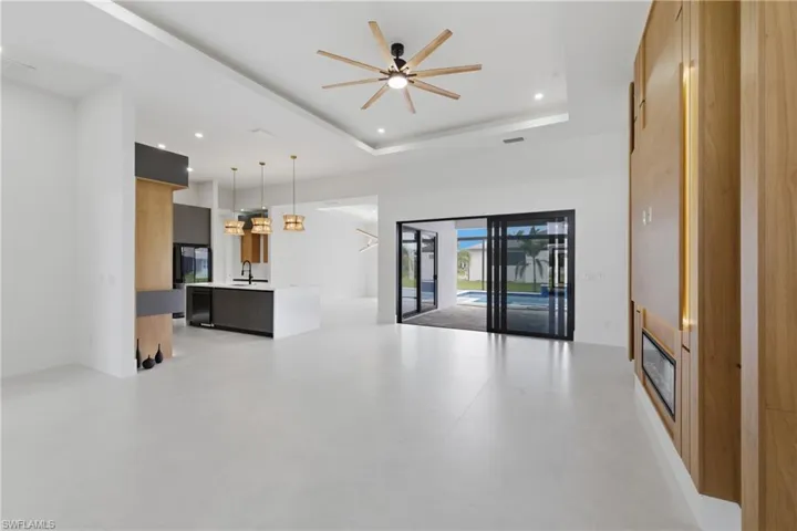 Unfurnished living room featuring ceiling fan, recessed lighting, and a high ceiling