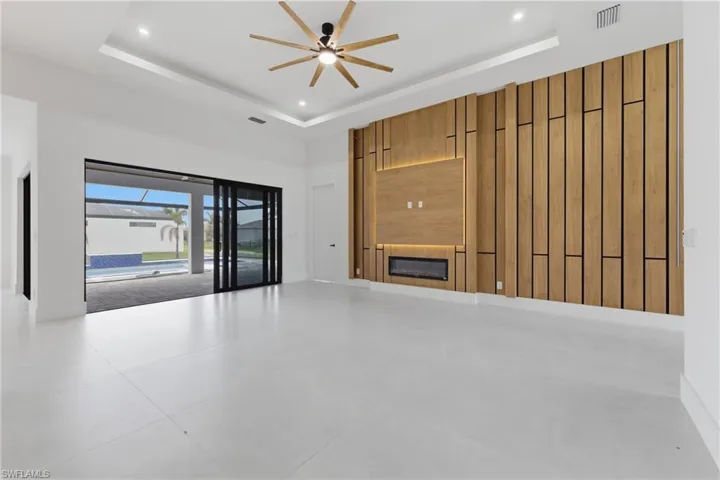 Unfurnished living room featuring a glass covered fireplace, ceiling fan, and a high ceiling