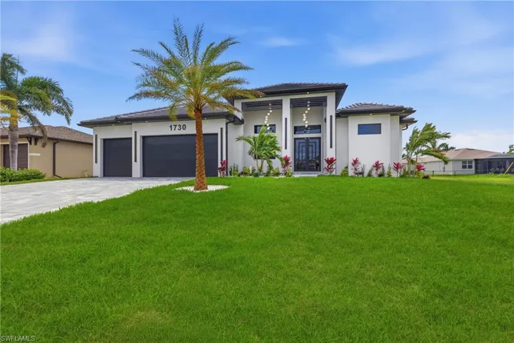 Prairie-style house with an attached garage, a front lawn, driveway, and stucco siding