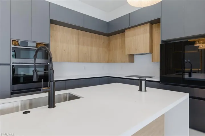 Kitchen with modern cabinets, two tone color scheme, dark stone countertops, and black appliances