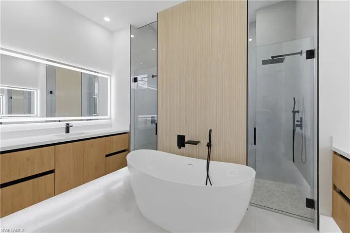 Bathroom featuring vanity, a marble finish shower, a soaking tub, recessed lighting, and light tile patterned floors