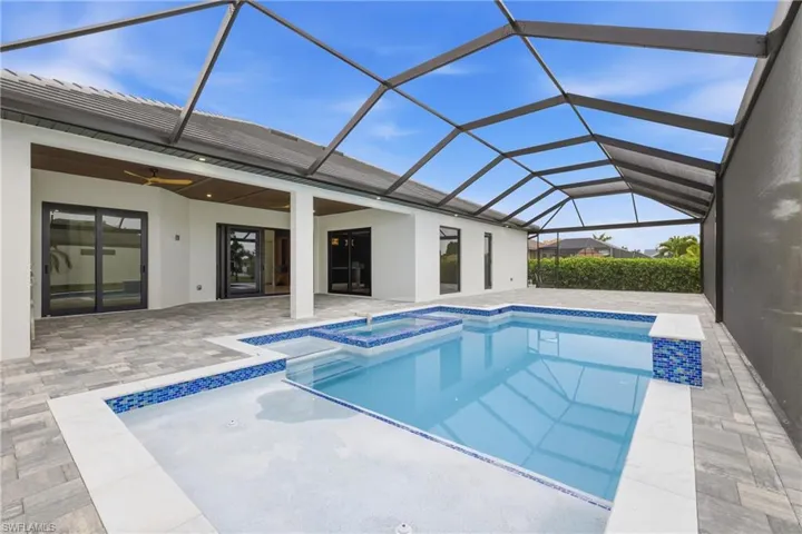 Relaxing pool / spa featuring a sunroom, a patio, and glass enclosure