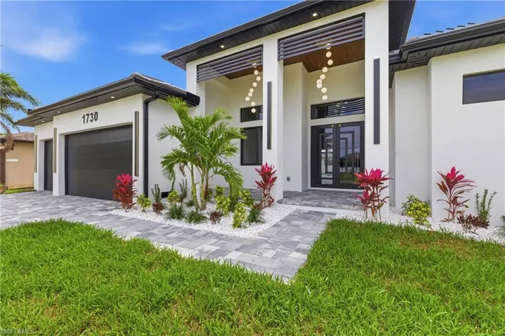 Entrance to property featuring stucco siding, french doors, a garage, and decorative driveway