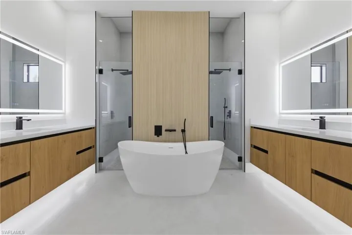Bathroom with two vanities, a stall shower, a freestanding bath, and finished concrete flooring