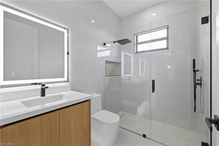 Bathroom with vanity and a marble finish shower
