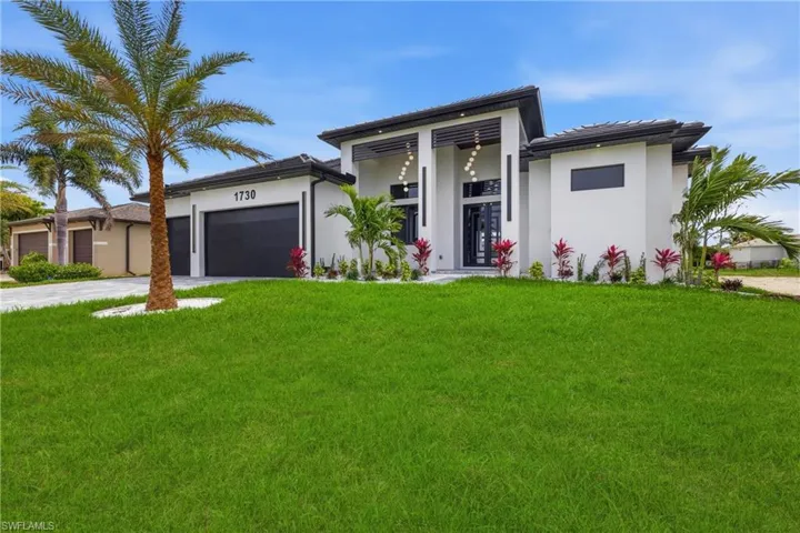 View of front facade with a front lawn, an attached garage, driveway, and stucco siding