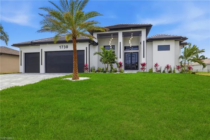 View of front of home with a front yard, a garage, driveway, and stucco siding