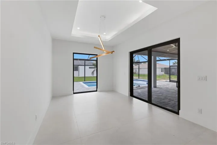Empty room with a sunroom, recessed lighting, a residential view, and a raised ceiling