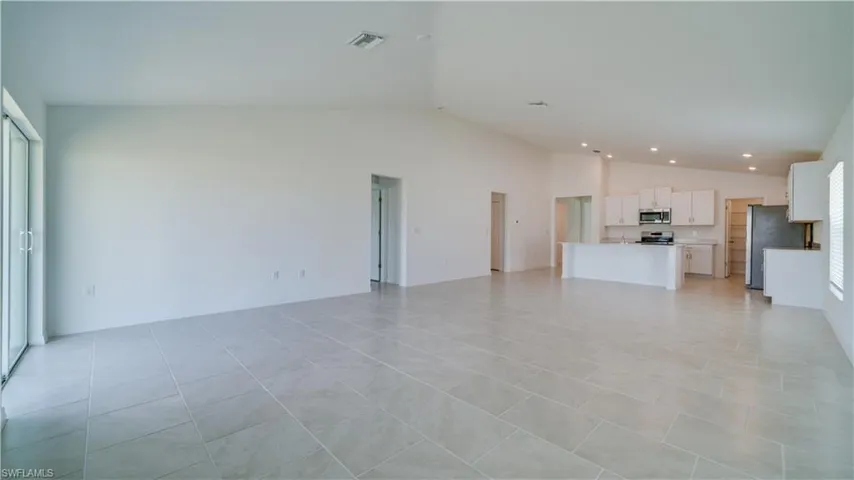Unfurnished living room with vaulted ceiling, light tile patterned floors, and recessed lighting
