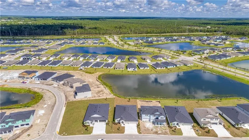 Aerial perspective of suburban area with a nearby body of water and a heavily wooded area