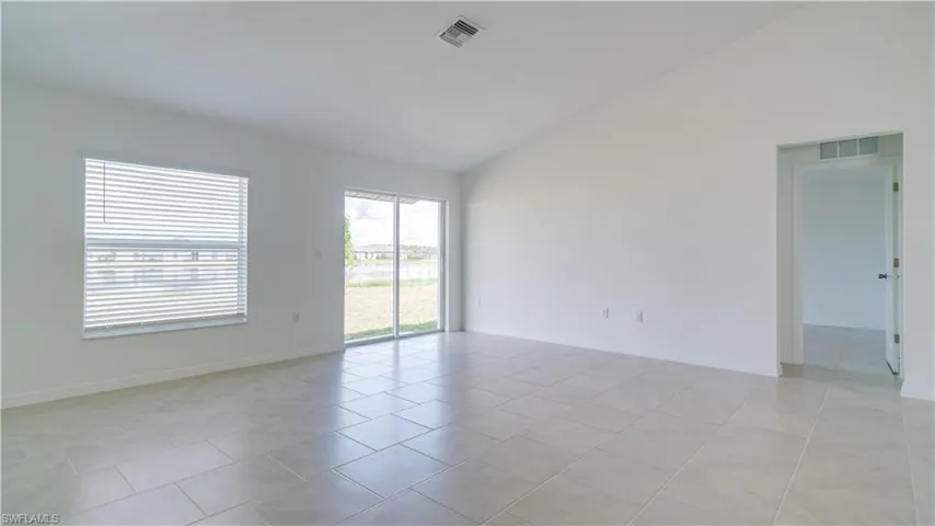 Spare room featuring lofted ceiling and light tile patterned floors