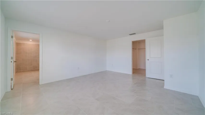 Unfurnished bedroom featuring a spacious closet and light tile patterned floors