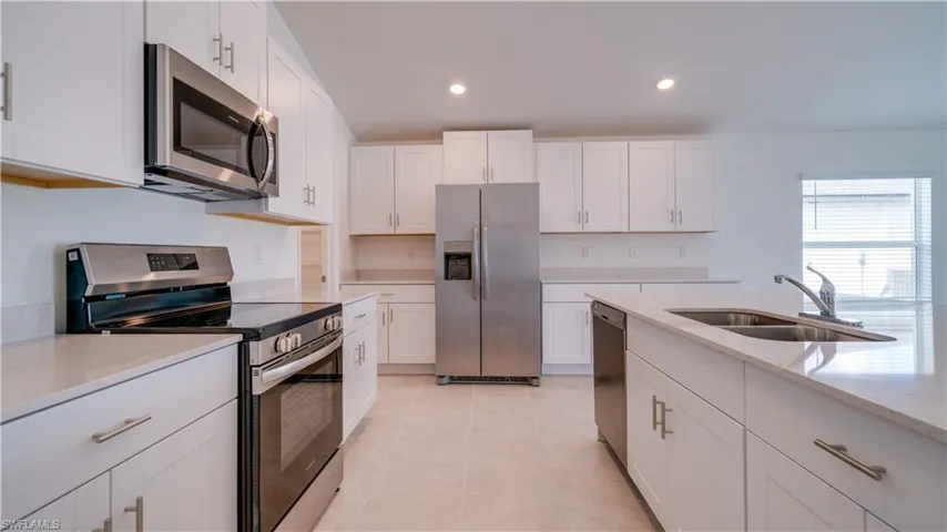 Kitchen with stainless steel appliances, light stone counters, white cabinetry, recessed lighting, and light tile patterned flooring