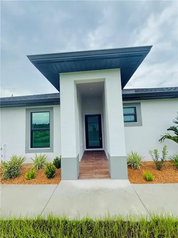 Doorway to property with stucco siding and roof with shingles