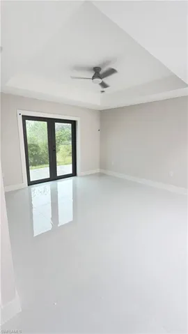 Unfurnished room featuring french doors, a ceiling fan, and a raised ceiling