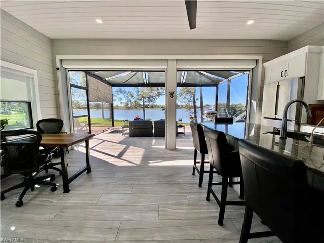 Dining area with a sunroom, recessed lighting, a water view, and wooden walls