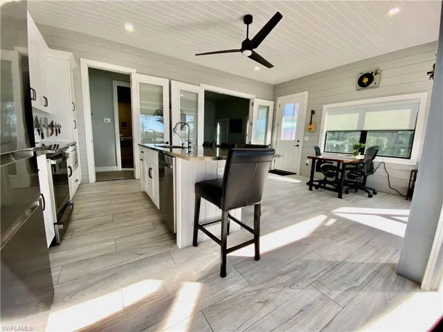 Kitchen with white cabinets, a kitchen island with sink, a kitchen breakfast bar, freestanding refrigerator, and recessed lighting