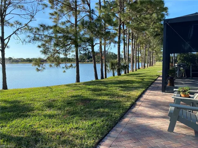 View of green lawn with a water view and a patio area