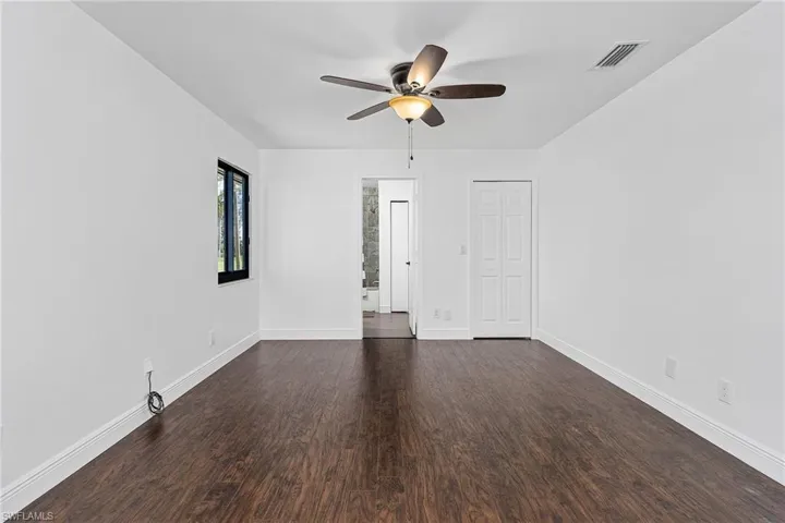Empty room with dark hardwood / wood-style flooring and ceiling fan
