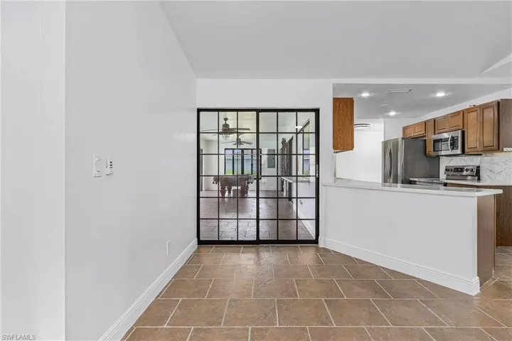Kitchen featuring tile flooring, backsplash, kitchen peninsula, and stainless steel appliances