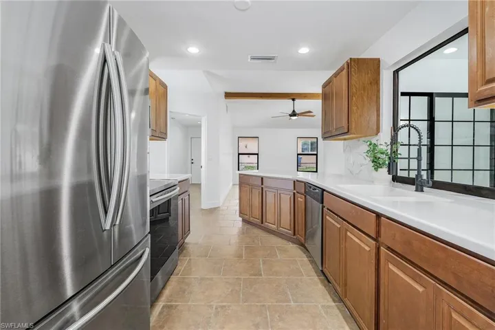 Kitchen with ceiling fan, stainless steel appliances, sink, and light tile floors
