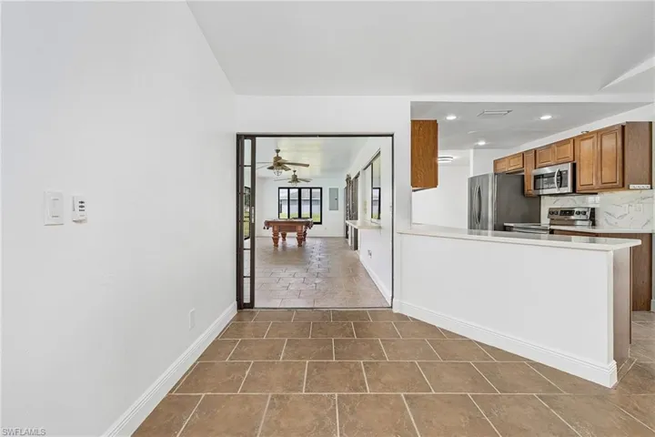 Kitchen with appliances with stainless steel finishes, ceiling fan, dark tile flooring, and tasteful backsplash