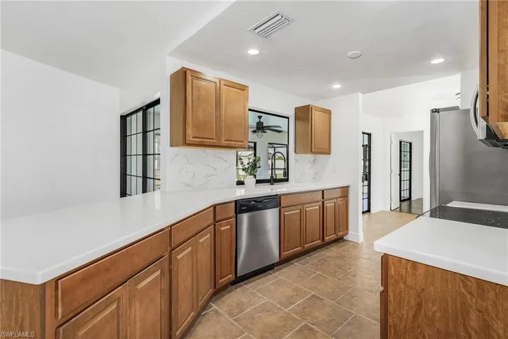 Kitchen with backsplash, ceiling fan, tile flooring, appliances with stainless steel finishes, and sink