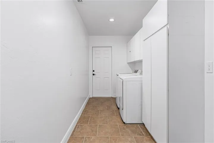Laundry area featuring cabinets, independent washer and dryer, and light tile floors