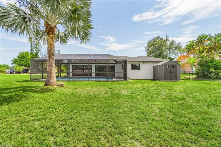 Back of property with a lanai, a storage shed, and a yard