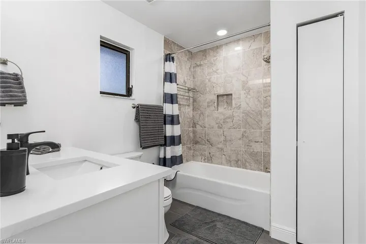 Full bathroom with tile flooring, vanity, toilet, and shower / tub combo with curtain