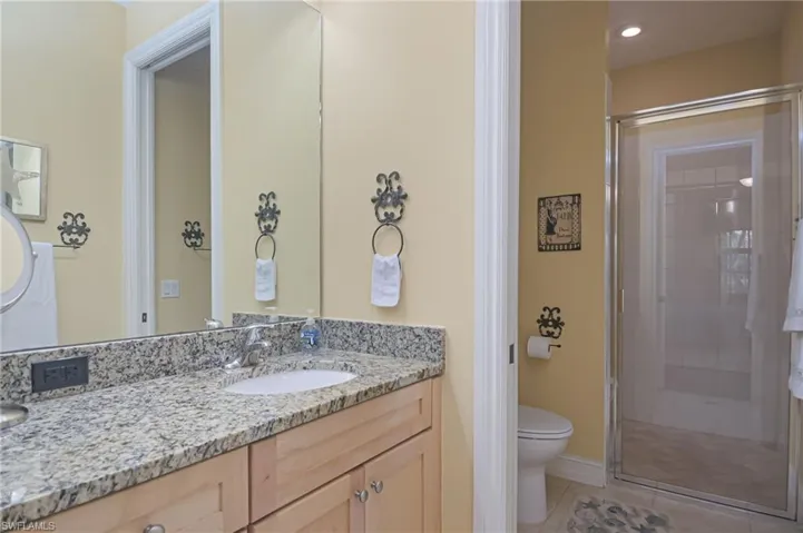 Bathroom featuring vanity with extensive cabinet space, walk in shower, toilet, and tile floors
