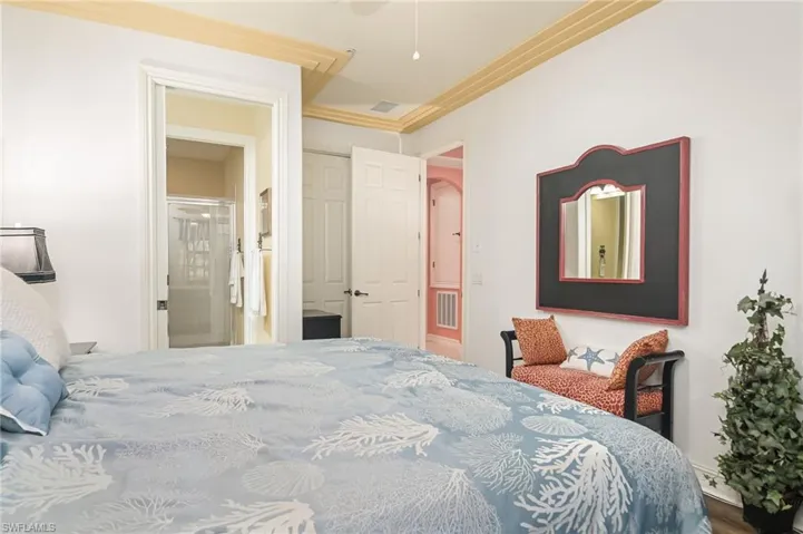 Bedroom with crown molding and connected bathroom